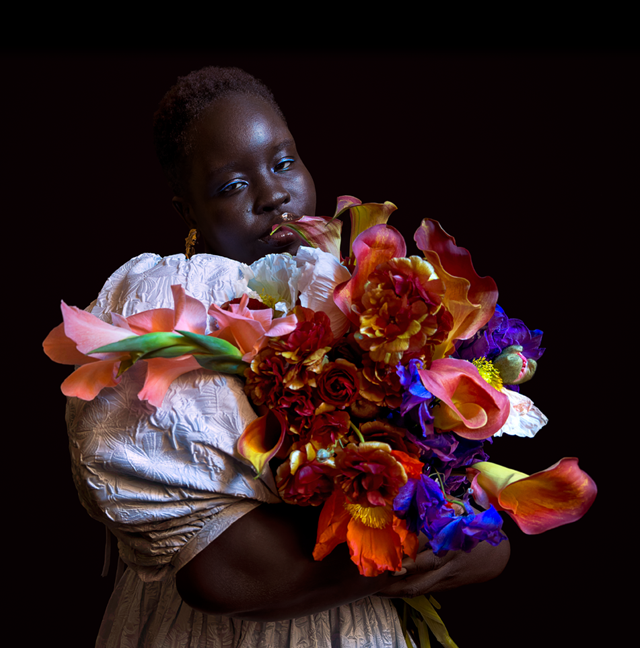 Foto con poca luz de una persona que sostiene un ramo colorido de flores.